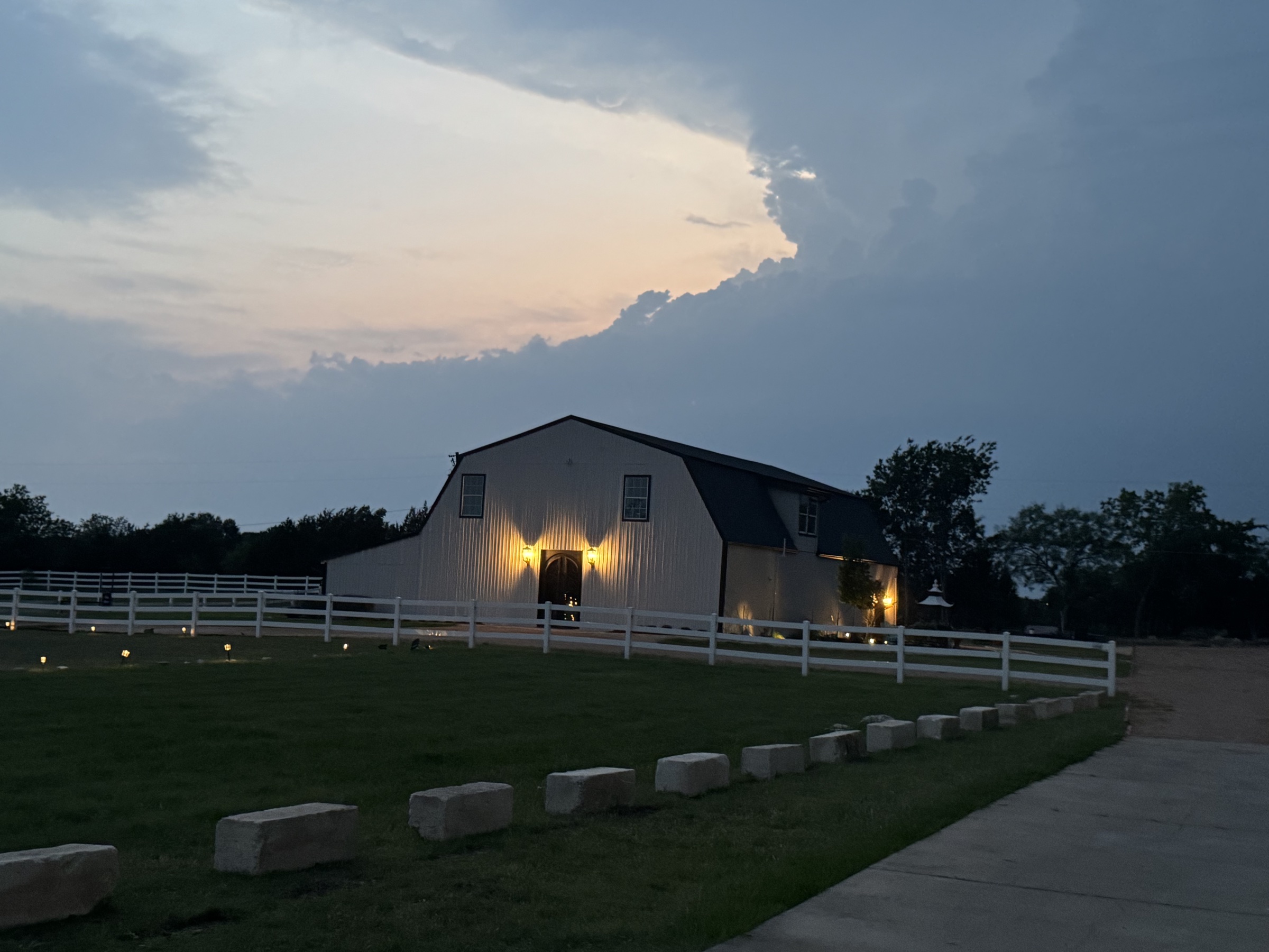 The barndominium venue at twilight beneath a dramatic Texas sky.