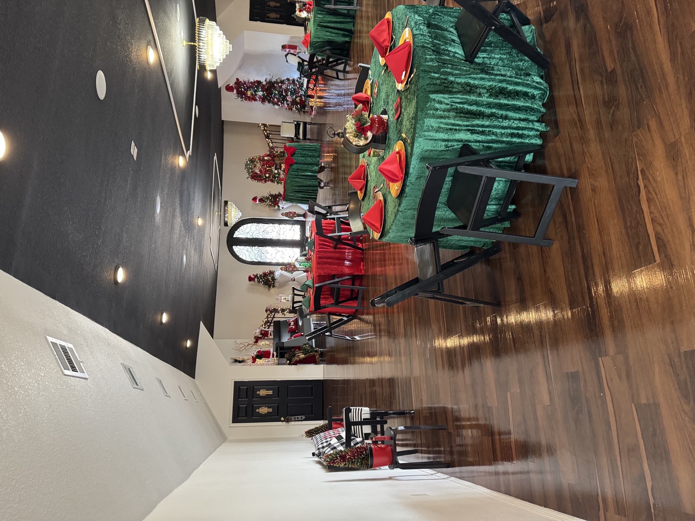 Christmas event setup at the venue — green velvet tables, red napkins, Christmas trees, and festive accents.